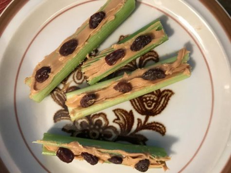 Celery with peanut and raisins on top placed on a plate