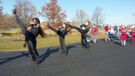the winter guard members are kicking their legs very high in the air and walking