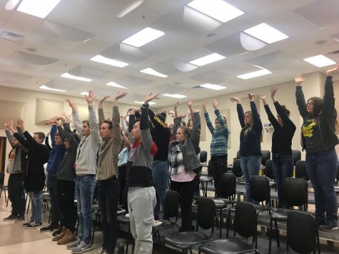 Students dance on risers in the choir room during rehearsal.