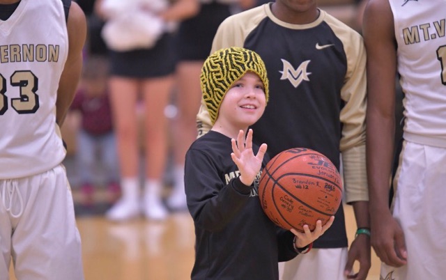 The+boy+with+cancer+is+holding+a+basketball+and+waving+to+the+croud.