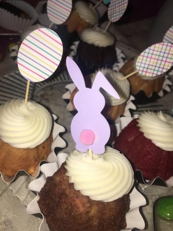 Easter-themed cupcakes with white icing and paper decoration on top.