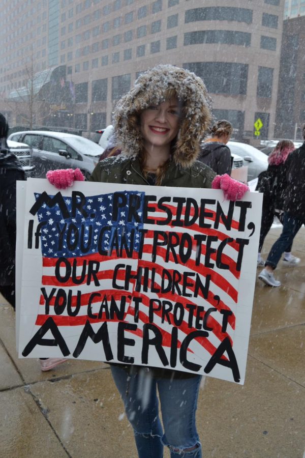MVC Staff Reporter Emma Clifton holds a poster that says, Mr. President, if you cant protect our children, you cant protect America.