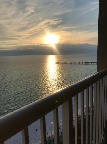 The view of the sun setting over the ocean from a condo balcony.