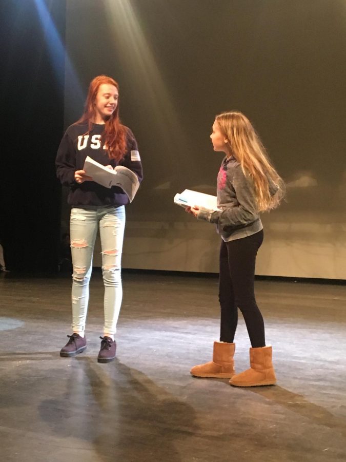 Lauren and Ava smile while reading off of their scripts.
