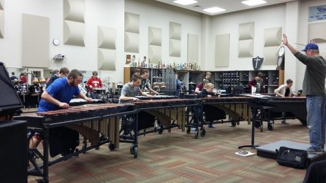 A conductor directs the indoor percussion members during a rehearsal.