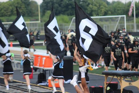 MV Cheerleaders run with flags to celebrate a touchdown