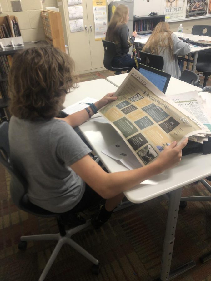 student reading physical copy of the newspaper