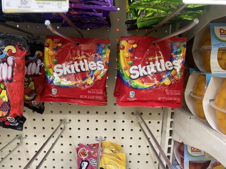 two bags of Skittles hanging on a store display
