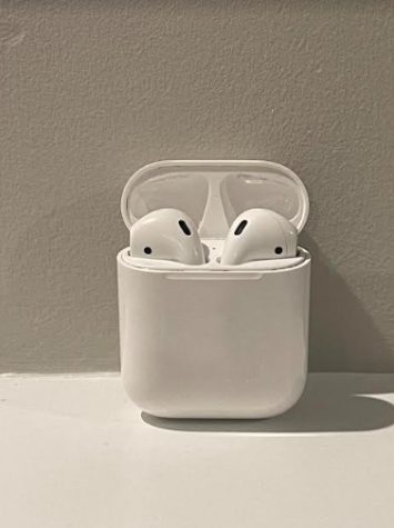 Airpods’ ear pieces inside the case, charging with a green or red light shining, showing the approximate battery life.
