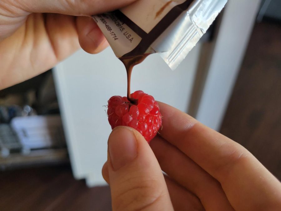 Melted chocolate being poured into a raspberry
