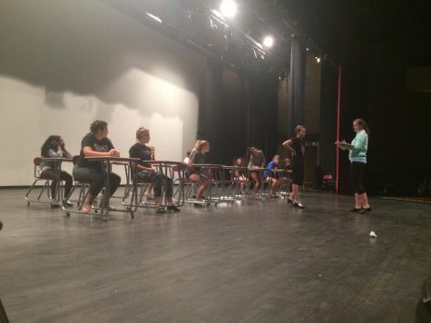 Thoroughly Modern Millie cast sitting in desks as part of dance