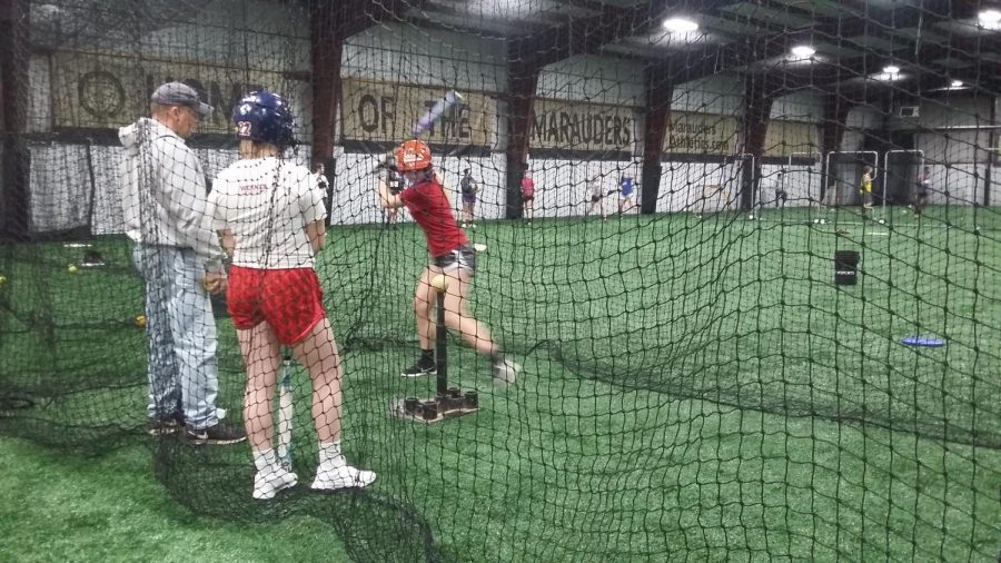 A softball player is winding up to hit the ball off of the tee.