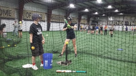 a softball player is in a net, getting ready to swing