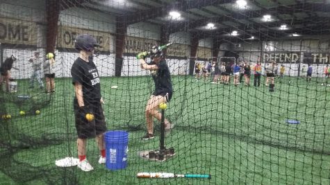 a softball player is in a net, getting ready to swing