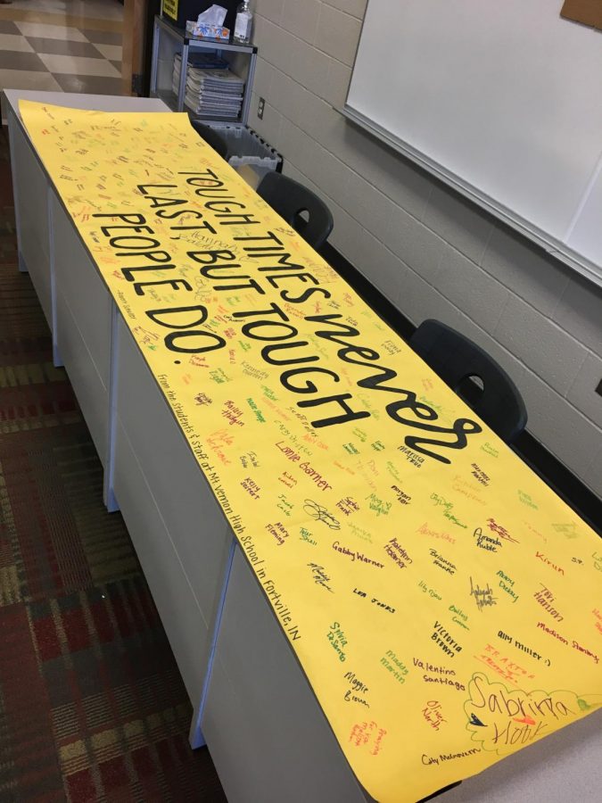 A banner on a desk says, "Tough times never last but tough people do."