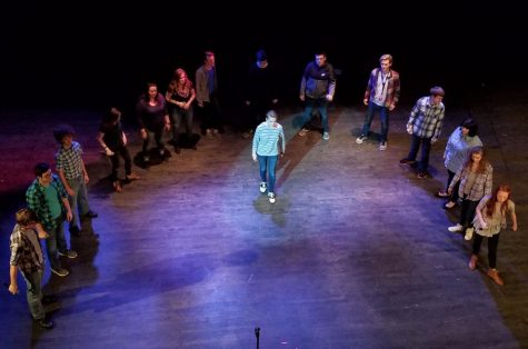 Peformers stand in a semicircle around a soloist onstage.