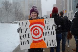 MVC Staff Photographer Lexi Price holds a poster that says, "Why is my body more policed than a gun?"