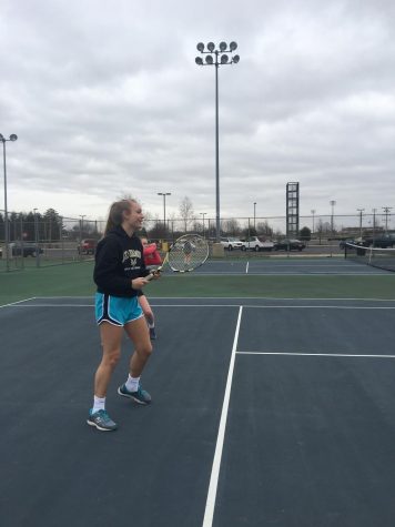 A tennis player has a racket in her hand, and is ready to hit the ball.