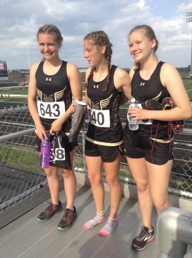 Three girls stand side by side and pose for a picture