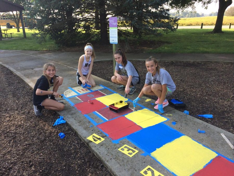 Students repaint the sidewalks at a local park as part of a service learning project