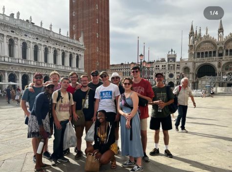 Students smiling for the photo in front of buildings