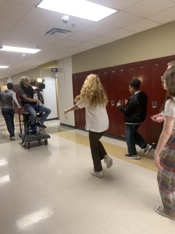 Photo of students dancing behind the moving camera. 